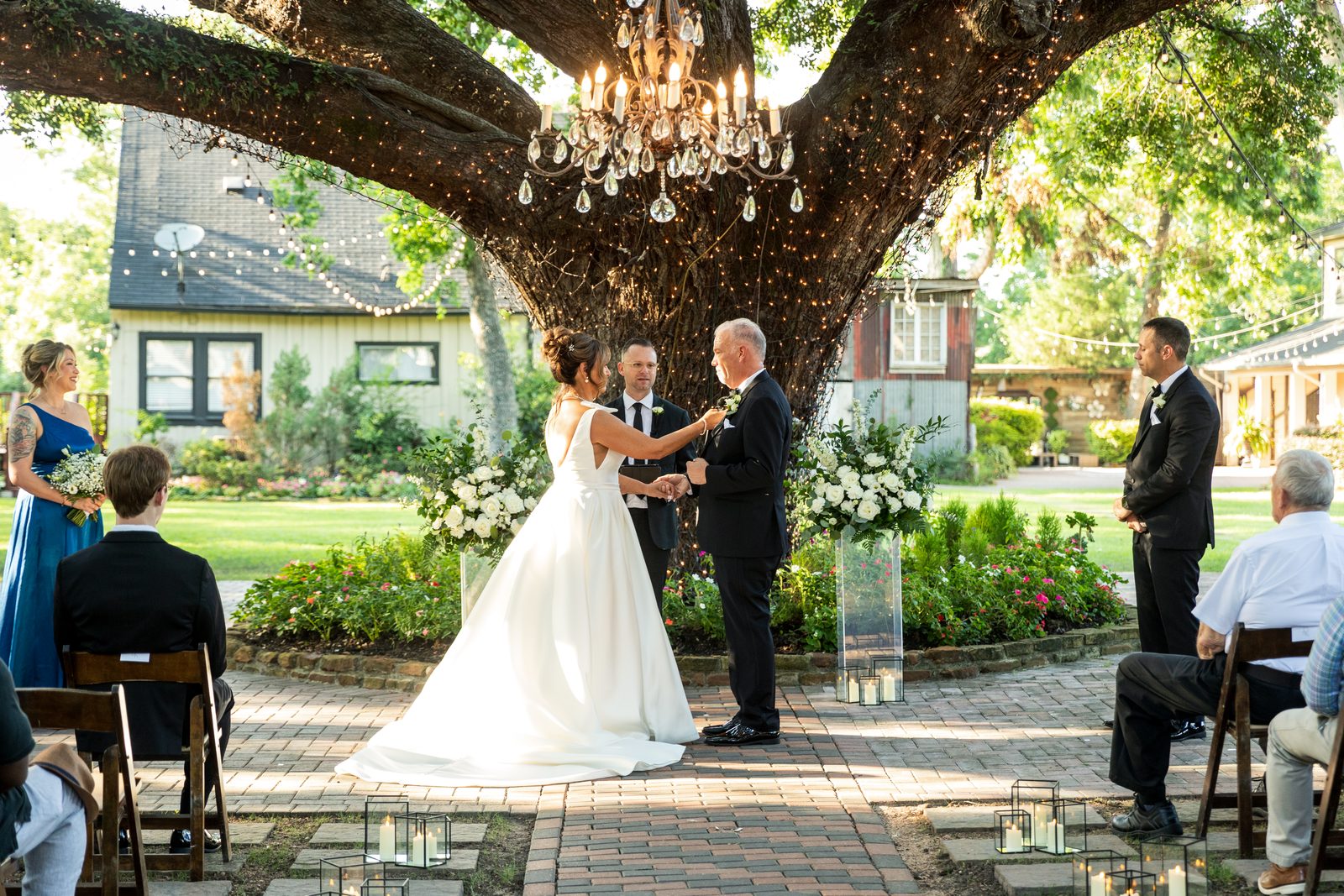 Couple at an outdoor altar beneath a large oak tree at golden hour
